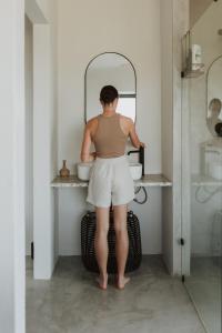 une femme debout devant un miroir de salle de bains dans l'établissement Spionkop Eco Cabin, 