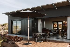 une terrasse avec une table, des chaises et un parasol dans l'établissement Spionkop Eco Cabin, 