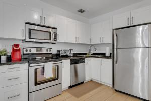 una cocina con armarios blancos y electrodomésticos de acero inoxidable en Gated 3Bd 2Bth Design Dist 10-min to Beach, en Miami