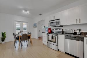 una cocina con armarios blancos y una mesa con sillas. en Gated 3Bd 2Bth Design Dist 10-min to Beach, en Miami