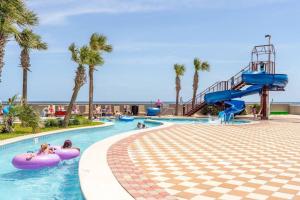 uma piscina num resort com palmeiras e escorregas em The Bluebird OBA at Phoenix West II em Orange Beach