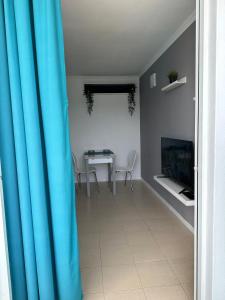 sala de estar con mesa y cortina azul en Golf del Sur Tenerife - Casa Barrera verde green park la corbeta, en San Miguel de Abona