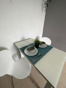 a white table with two plates and a plant on it at Golf del Sur Tenerife - Casa Barrera verde green park la corbeta in San Miguel de Abona