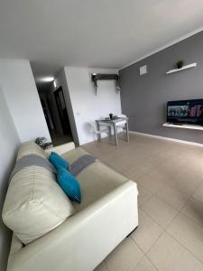 a white couch with blue pillows in a living room at Golf del Sur Tenerife - Casa Barrera verde green park la corbeta in San Miguel de Abona