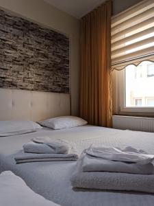 een slaapkamer met 2 bedden en een bakstenen muur bij 22 OTEL in Edirne