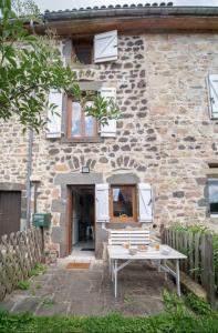 a stone house with a bench in front of it at ⟬La Maisonnette de Séverine⟭ in Saint-Genès-Champanelle