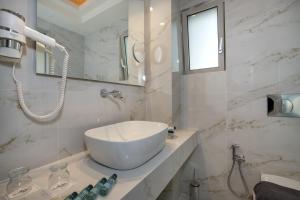 a white bathroom with a sink and a mirror at Vantaris Luxury Beach Resort in Georgioupolis