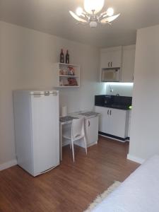 a kitchen with a table and a refrigerator in a room at Residencial Vitor Studio 1 in São José dos Pinhais