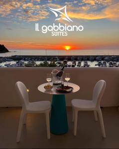 San Marco di Castellabate的住宿－Il Gabbiano Suites，阳台上配有带2把椅子和酒杯的桌子