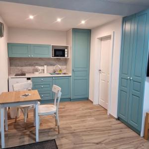 a kitchen with blue cabinets and a table and chairs at Ako doma in Poltár