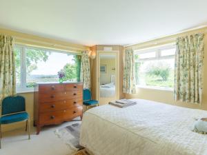 a bedroom with a bed and a dresser and windows at Curlew Cottage in Hexham