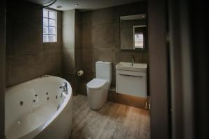 a bathroom with a tub and a toilet and a sink at The Lake Isle Restaurant with rooms in Uppingham