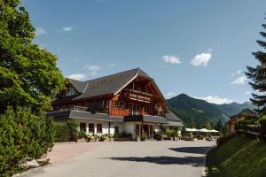 a large wooden building with mountains in the background at Almdorf Reiteralm in Schladming