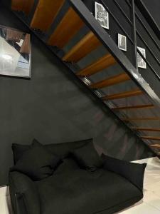 un divano posto sotto una scala in una stanza di NEW Insta Worthy B&W Designer Loft in Cheras, KL 