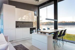 a kitchen with white cabinets and a table with chairs at Villa Noir Muurla - Premium - Lakefront - Stylish in Salo
