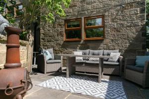 a patio with chairs and a bench and a brick wall at Remarkable 4-Bed House Near Leeds Airport in Yeadon