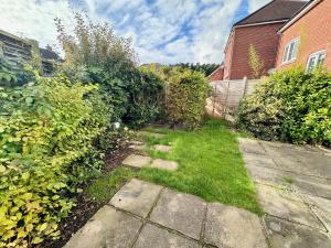 a backyard with a yard with grass and bushes at Elvetham Nest Guesthouse, Basingstoke in Basingstoke