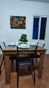 a dining room table with chairs and a painting on the wall at Apartamento Pradera's in Escuintla