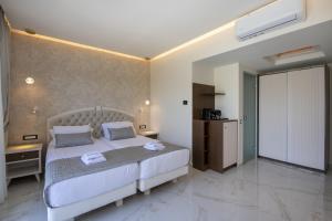 a bedroom with a white bed and a kitchen at Vantaris Luxury Beach Resort in Georgioupolis