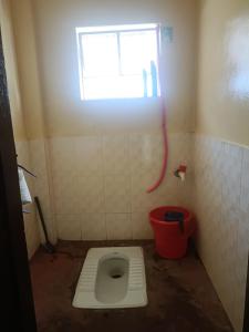 ein Bad mit einem WC, einem Fenster und einem roten Eimer in der Unterkunft Banraplang syngkrem house in Shillong