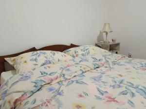 a bed with a comforter with flowers on it at Apartman 019 in Zaječar