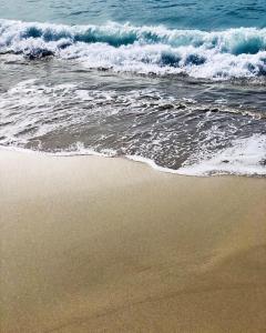 a sandy beach with waves crashing on the ocean at Palm Beach in Ajaccio