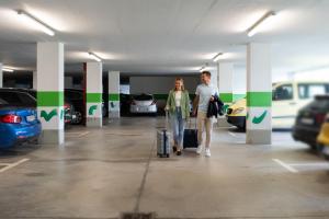 un hombre y una mujer caminando por un estacionamiento en Hotel Alpenflora, en Castelrotto
