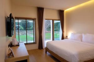 a bedroom with a bed and a large window at Pai Nam Now in Pai