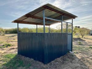 Kambu Mara Camp في Sekenani: مبنى ازرق بسقف في الميدان