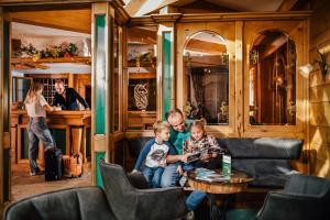 Un uomo e due bambini seduti in una stanza del treno di Appartement Hotel Garni Alpenstüble a Mittelberg