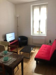 een woonkamer met een rode bank en een tafel bij Appartement 30m² RDC 2 pièces in Joigny