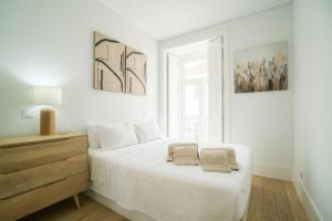 a white bedroom with a bed with two towels on it at Luxury condo in heart of Baixa-Chiado in Lisbon