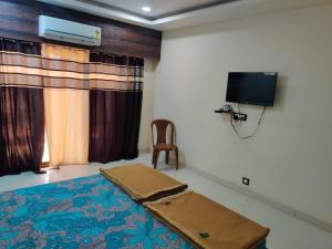 a room with a bed and a tv and a chair at Siddhivinayak Resort NX in Malvan