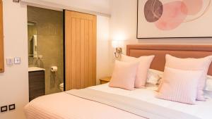 ein Schlafzimmer mit einem weißen Bett mit rosa Kissen in der Unterkunft St Annes Beach Apartments in Lytham St Annes