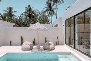 ギリ・トラワンガンにあるCahaya Villas - Luxury Villa With Private Poolの家の上に椅子2脚とパラソル付きのプールがあります。