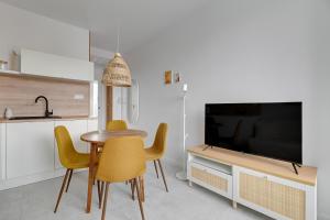 a kitchen with a table and chairs and a television at Przypływ by Grand Apartments in Gdynia