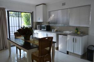 une cuisine avec des armoires blanches et une table avec des chaises dans l'établissement Bryanston Elgin - Cottage 1, à Johannesbourg