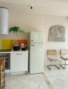 a kitchen with a white refrigerator and a table and chairs at Groovy Caparica Gem with Large Sunny Terrace in Costa da Caparica