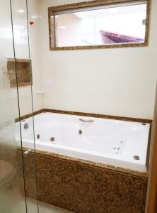 a bath tub in a bathroom with a window at Casa - Luxo e Conforto, Hidromassagem a 50m do Mar in São Mateus