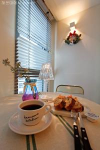 a table with a cup of coffee and a plate of food at Haeundae Bona Travel in Busan