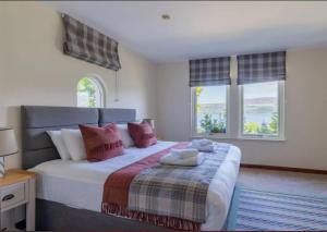 a bedroom with a large bed with two windows at Loch Ness Cottages in Brackla