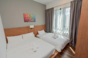 two beds in a room with a window at Ipoh Tambun Sunway Onsen Suite 3R2B Maya in Tambun