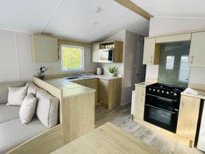 a small kitchen with a couch and a stove at Curlews Nest, Rockley Park in Hamworthy