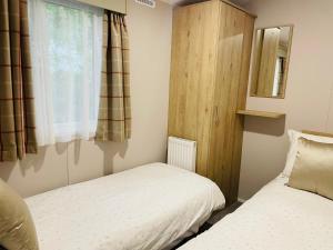 een kleine slaapkamer met 2 bedden en een raam bij Curlews Nest, Rockley Park in Hamworthy