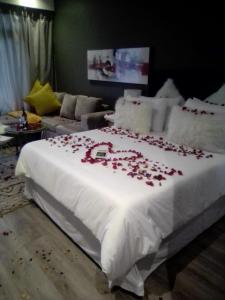 a bed with rose petals on it in a room at Menylyn Maine Residences Trilogy 913 in Pretoria