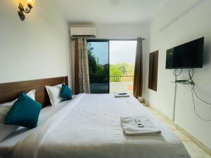 een slaapkamer met een bed, een televisie en een raam bij ZEKE HOTELS in Bangalore
