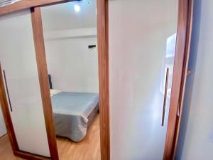 a small bedroom with a bed and a mirror at Lindo apto na Enseada - Guarujá - 8 min da praia in Guarujá +25 photos