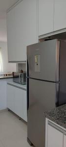 a kitchen with a stainless steel refrigerator and white cabinets at Apartamento Aconchegante in Capitólio