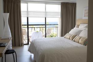 a bedroom with a bed and a view of the ocean at Sandy Beach Hotel & Spa - ex Sentido in Larnaca