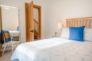 una camera da letto con un letto blu e bianco e uno specchio di Douglas Cottage - Seasgair Lodges a Boat of Garten